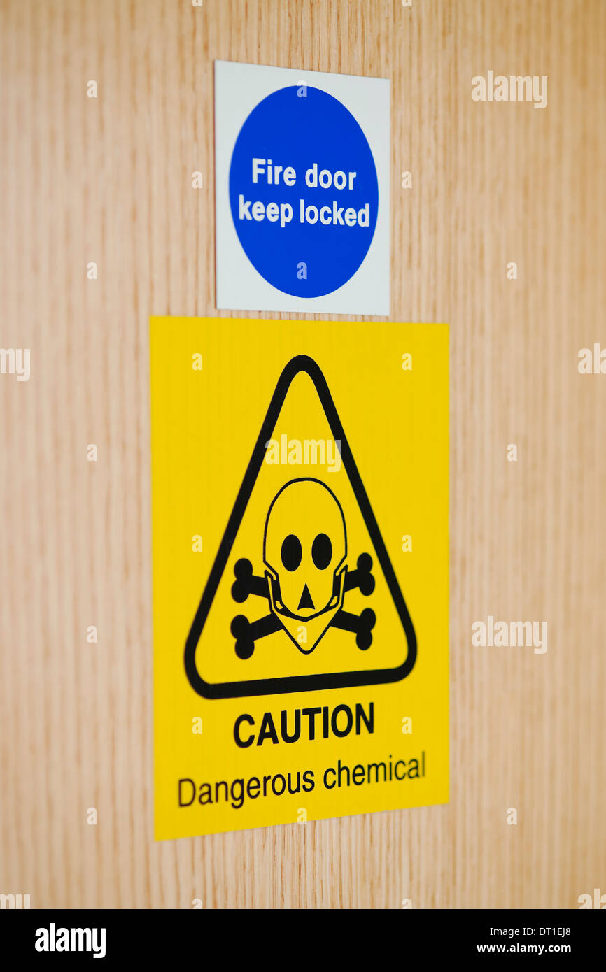 Close up of Fire door and dangerous chemical signs on interior wooden door England UK United Kingdom GB Great Britain Stock Photo