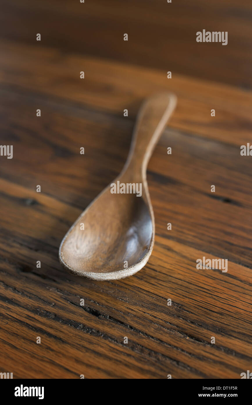 A smooth polished wooden ladle or spoon on a grained wooden tabletop Stock Photo