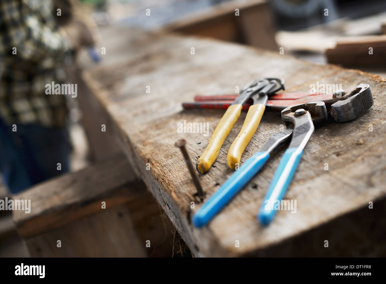 A reclaimed lumber workshop A person at a workbench and tools grippers and  pliers lined up on a plank of wood Stock Photo - Alamy