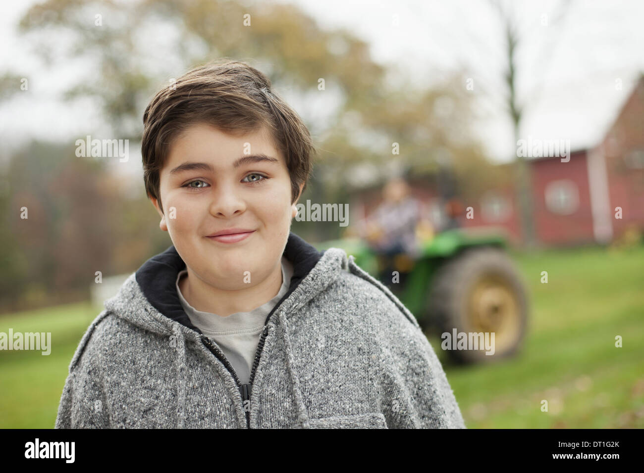 A boy on an organic farm beside a small tractor Stock Photo