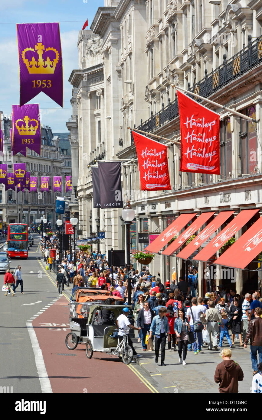 Busy pavement at famous Hamleys toy shop business Regent Street banners celebrating the Anniversary of Queen Elizabeth coronation London England UK Stock Photo