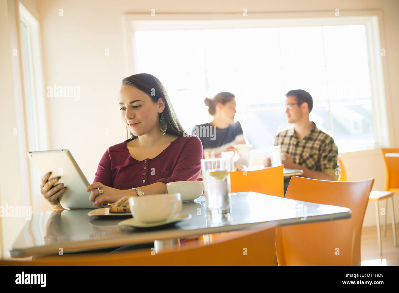 A woman in a coffee shop reading using a tablet computer Stock Photo