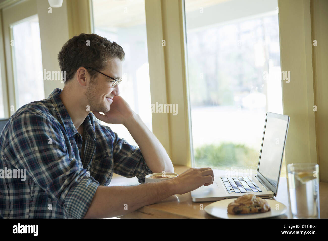 A young man sitting at a table using a laptop computer Stock Photo