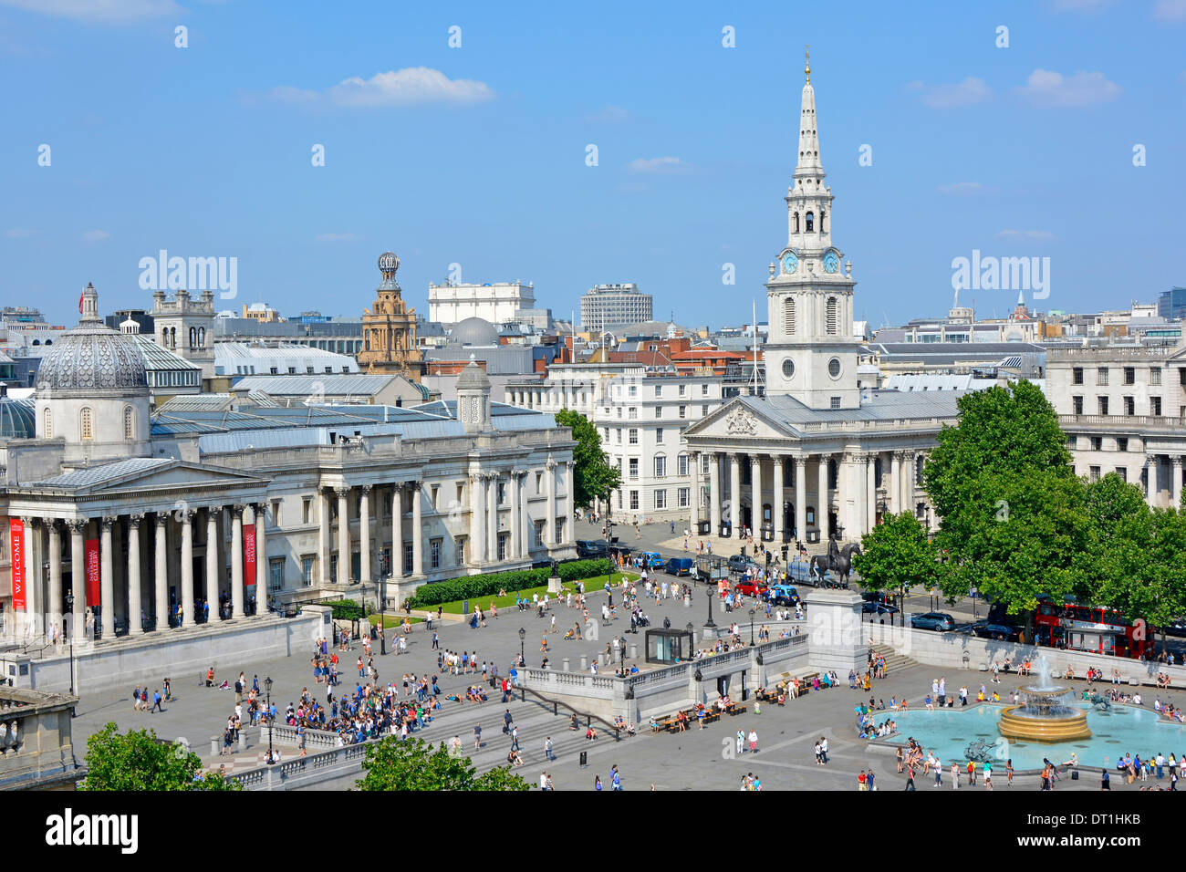 Aerial view tourists & people blue sky day in Trafalgar Square includes National Gallery colonnade spire of St Martin in the Fields London England UK Stock Photo