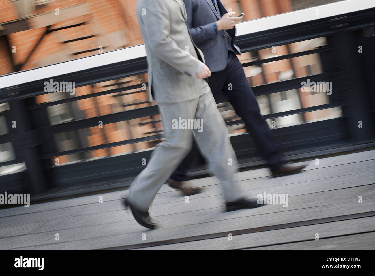 Two men in business clothes walking along a city sidewalk Stock Photo ...