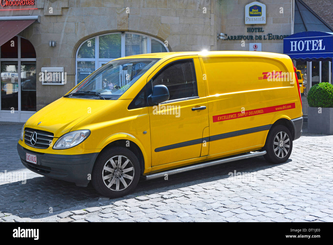 Side and front view Yellow DHL Mercedes Benz delivery van parked up outside Best Western Hotel in Brussels Belgium Europe EU Stock Photo