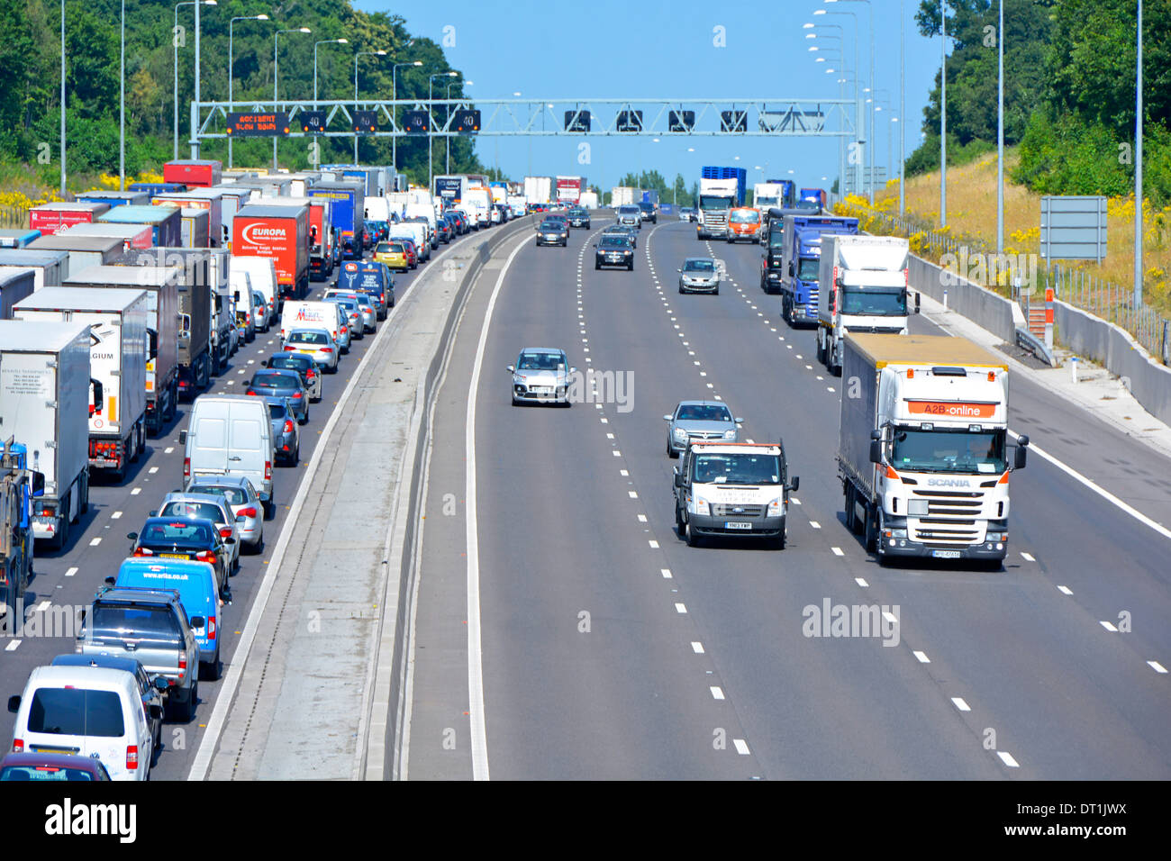 Four lane M25 motorway free flowing light traffic passing gridlocked queues of (mainly) trucks with articulated trailers Stock Photo
