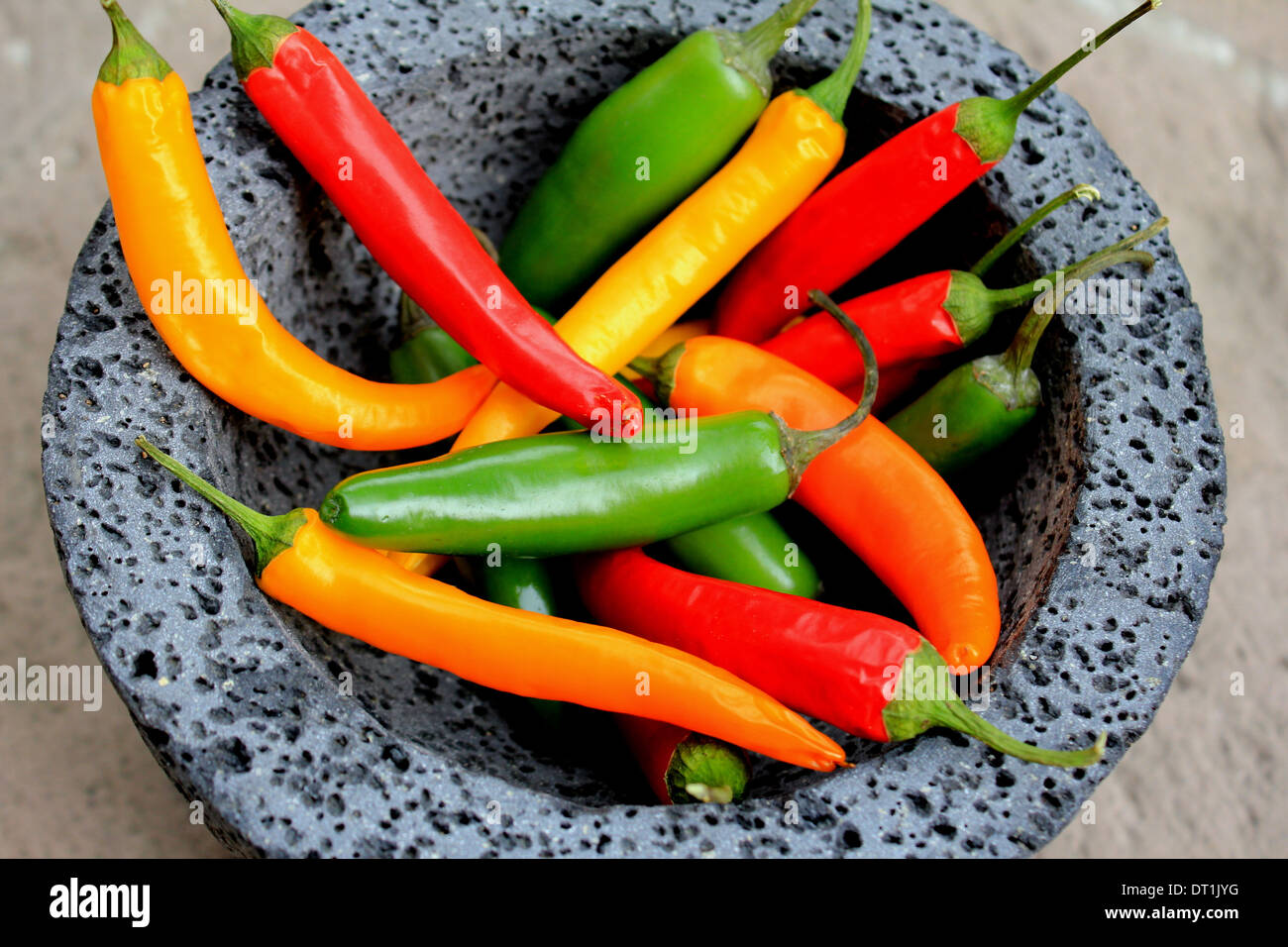 Red, green and yellow chilli peppers, in a stone molcajete,  Mexico Stock Photo