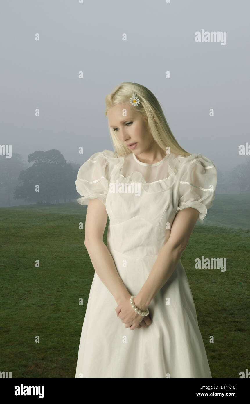 Sad woman standing in a misty field Stock Photo