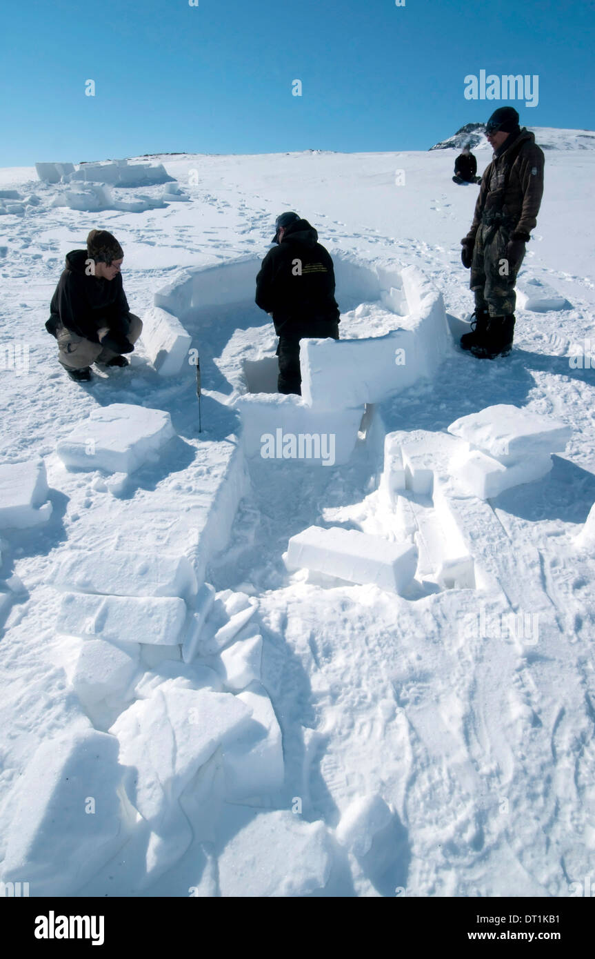Inuit cutting snow blocks using a saw and a knife to make an igloo, Nunavut, Canada, North America Stock Photo