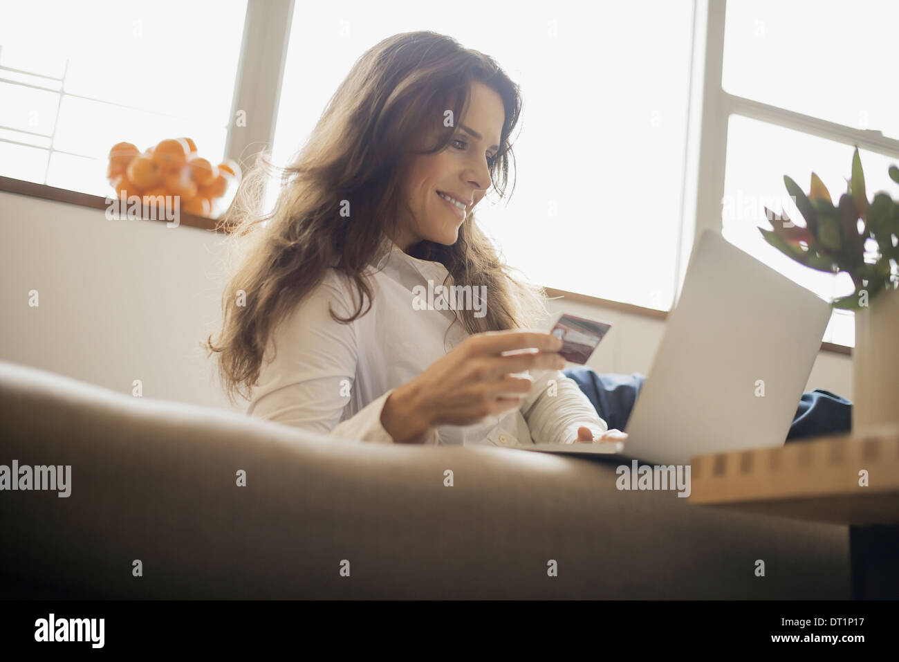 Woman on-line shopping on laptop on sofa with credit card Stock Photo