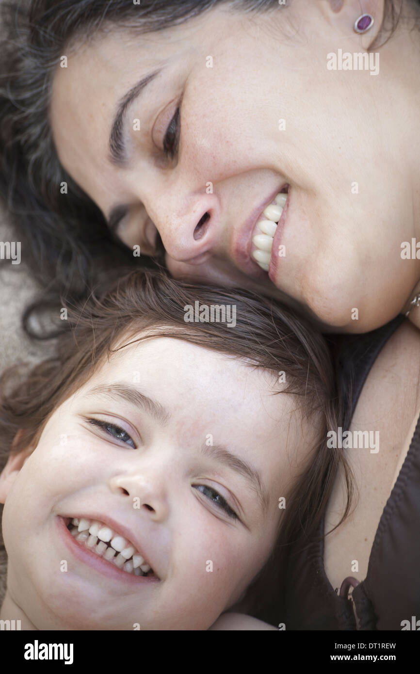 A close up of a mother and daughter lying with their heads together smiling and laughing Stock Photo