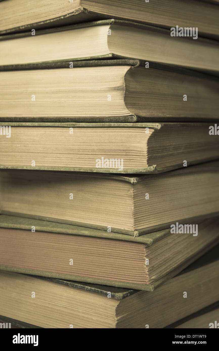 A stack of old hard cover books with worn edges and aged yellowing paper Stock Photo