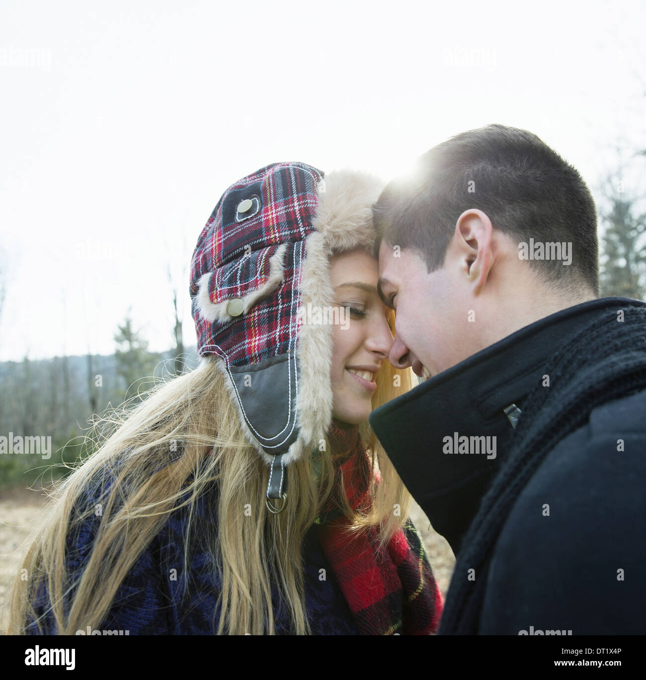 A couple young man and woman face to face embracing outdoors on a cold winter day Stock Photo