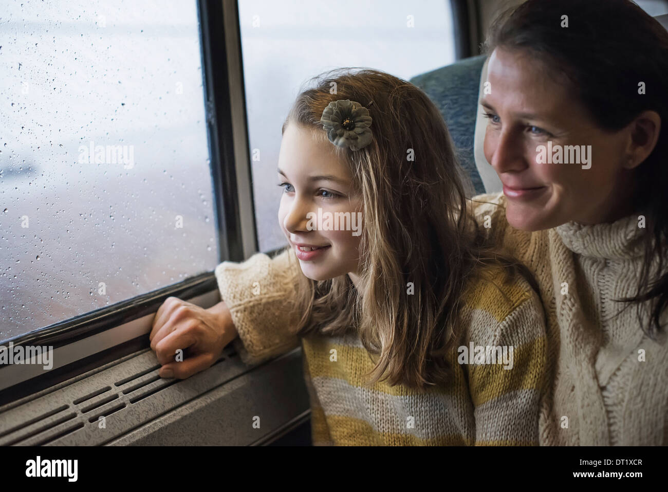 A man and a young girl sitting beside the window in a train carriage looking out at the countryside Smiling in excitement Stock Photo