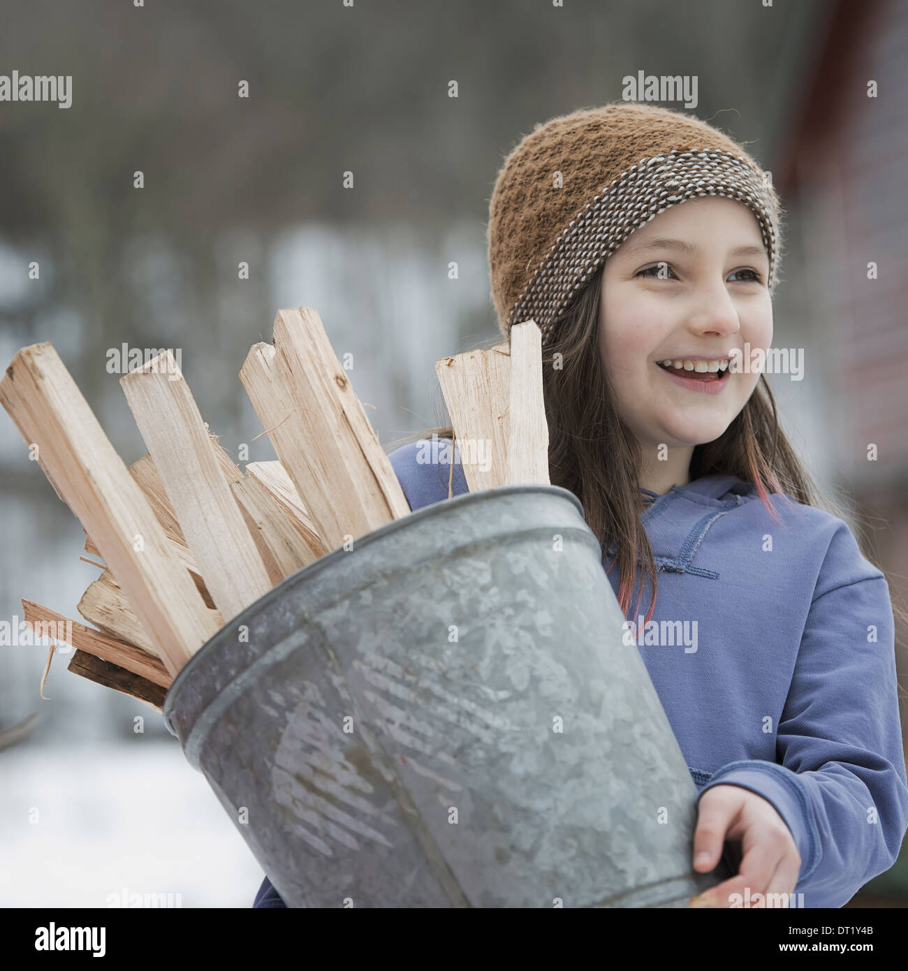 An organic farm in winter in New York State USA A girl carrying a bucket full of kindling and firewood Stock Photo