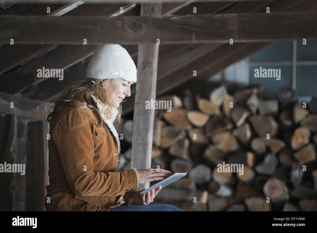 An organic farm in upstate New York in winter A woman sitting in an outbuilding using a digital tablet Stock Photo