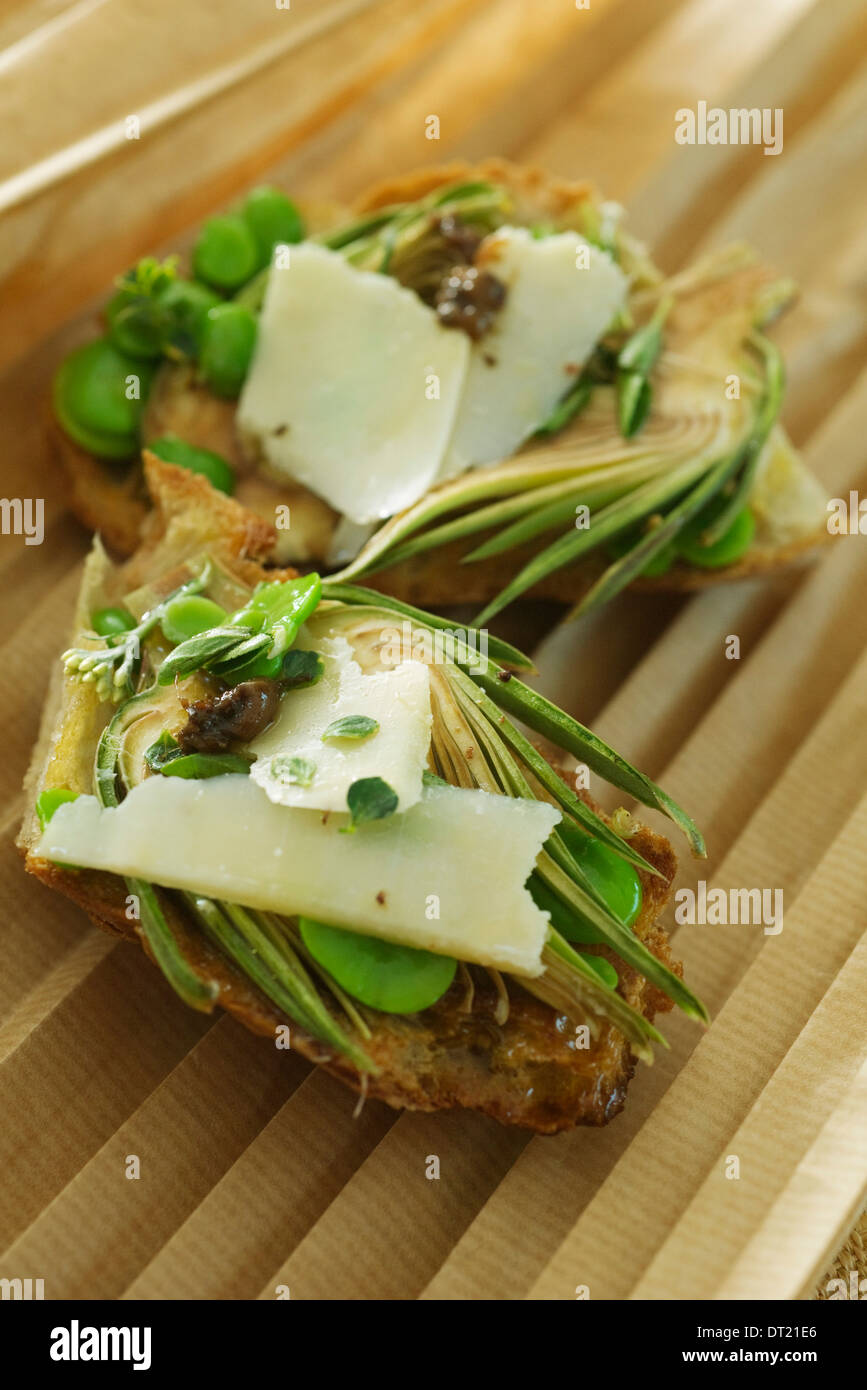 Artichokes parmesan on toast with anchovy dressing Stock Photo