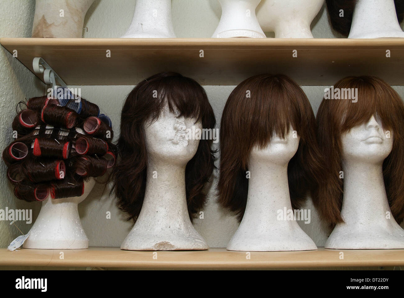 Long brown wigs on mannequins, headstands, in wig makers studio, salon