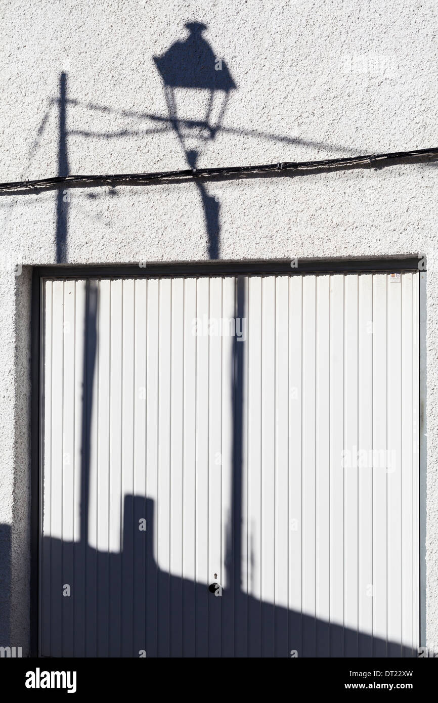 Shadows of lampost and pole with cable on garage door and wall. Stock Photo