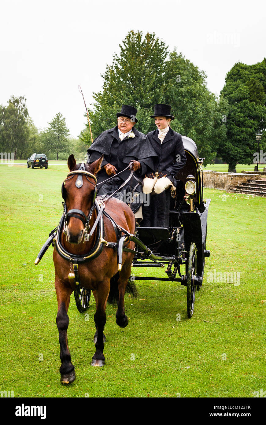 Wedding horse and carriage departing from a venue in private parkland in the rain Stock Photo