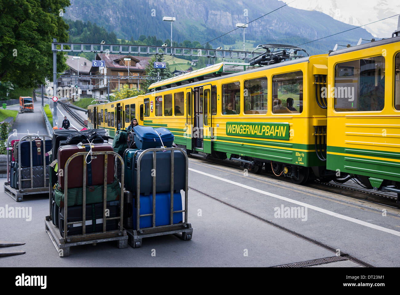 Wengen railway station showing incline up to the alpine peaks and trolley loads of tourist luggage waiting for the next train Stock Photo