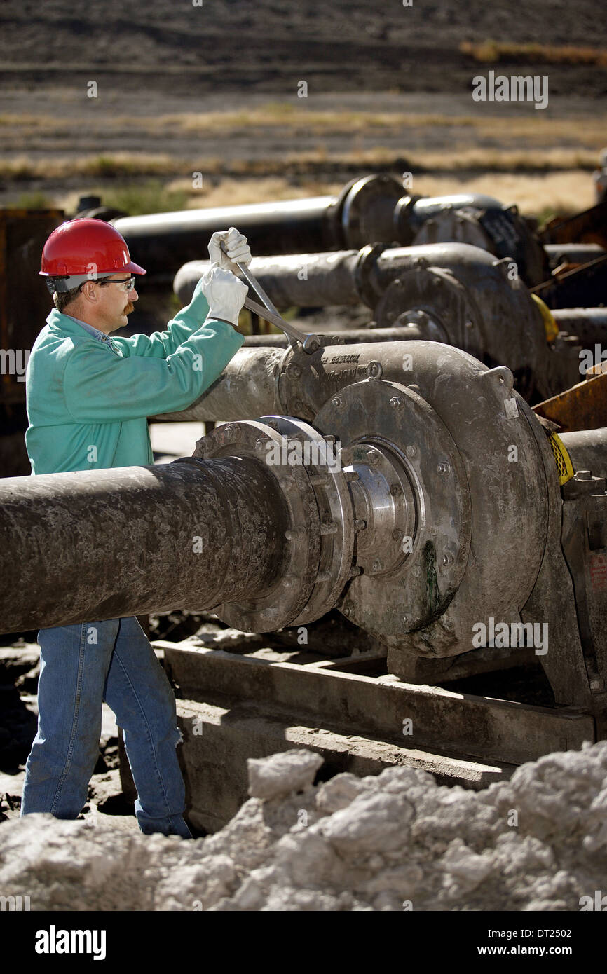 A laborer performs maintenance on an industrial pumping station. Stock Photo