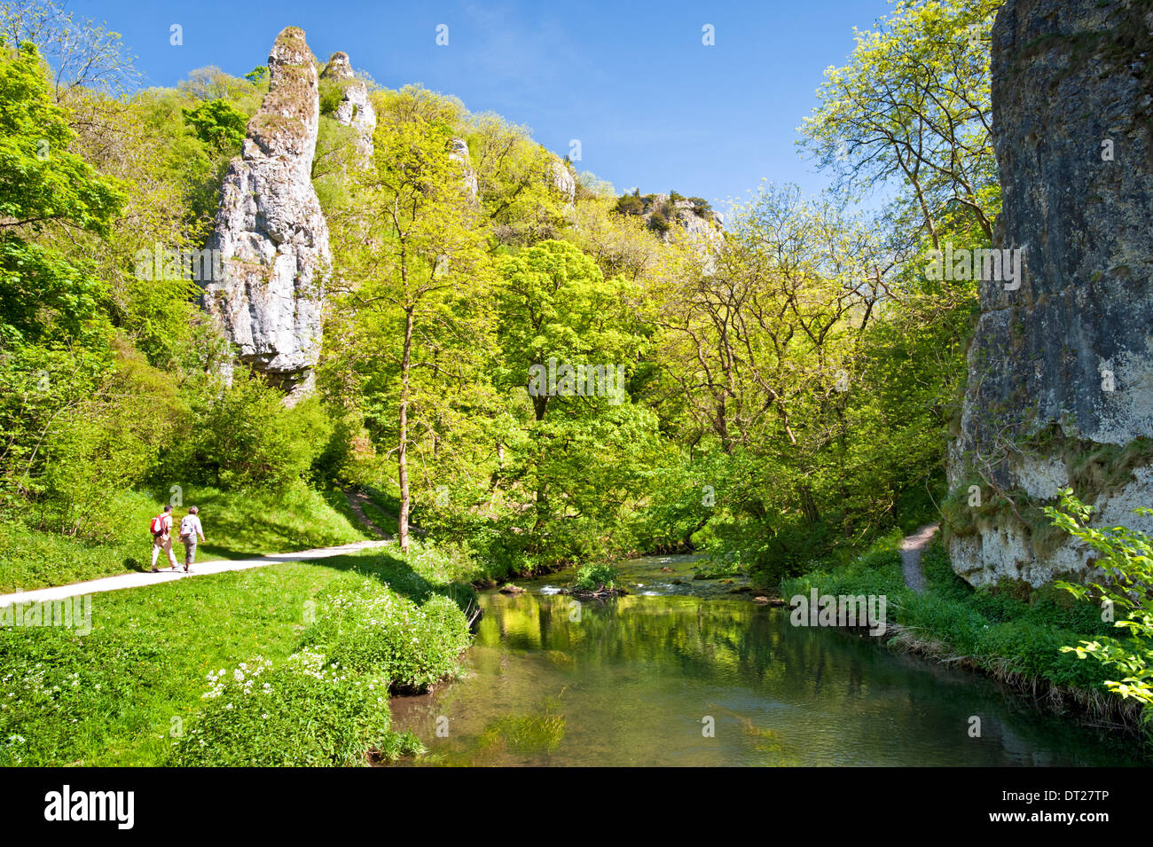 Walkers by River Manifold, Passing Ilam Rock & Pickering Tor, Dovedale, Peak District National Park, Derbyshire, England, UK Stock Photo