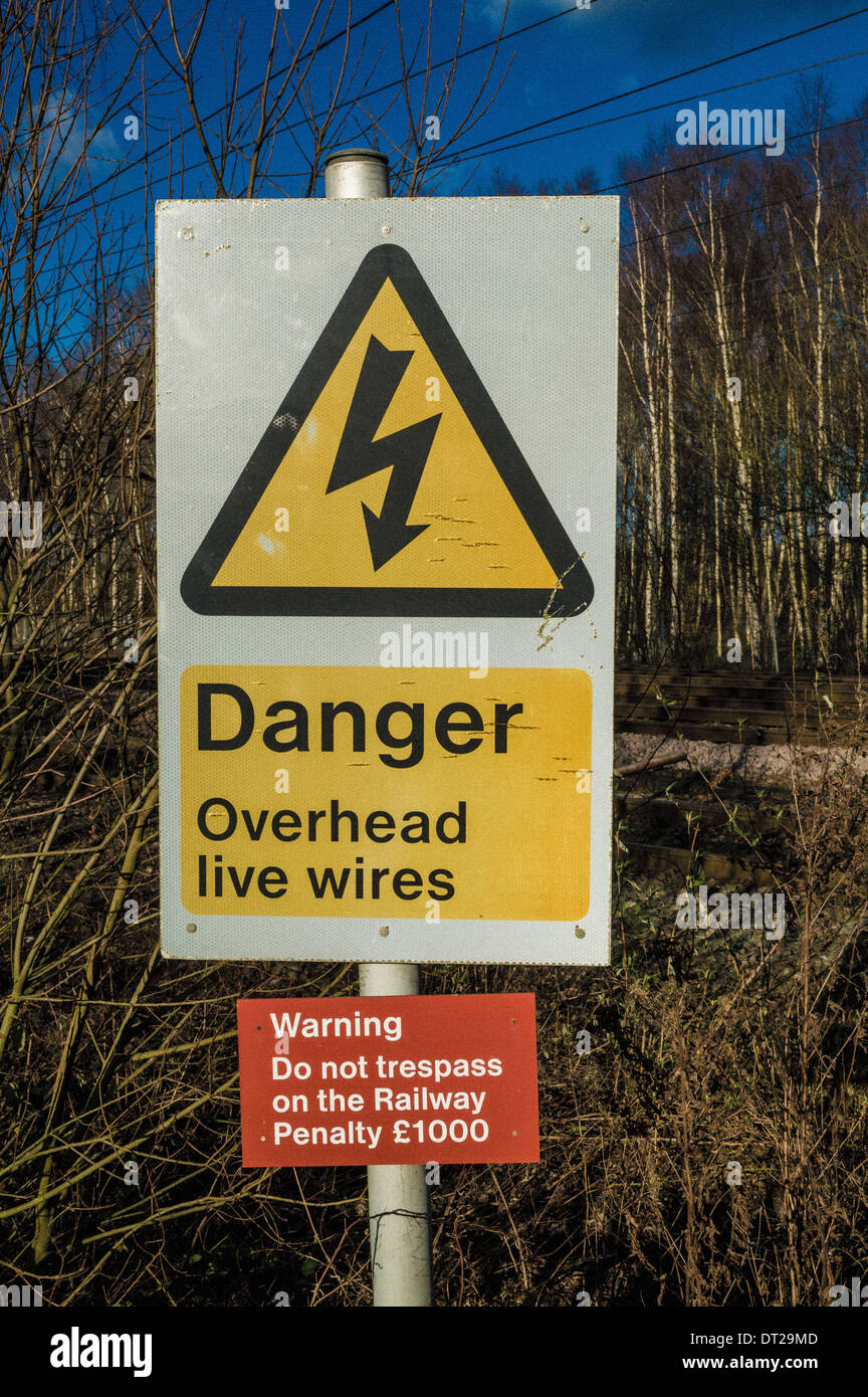Danger overhead wires and trespass sign at railway line in the UK. Stock Photo