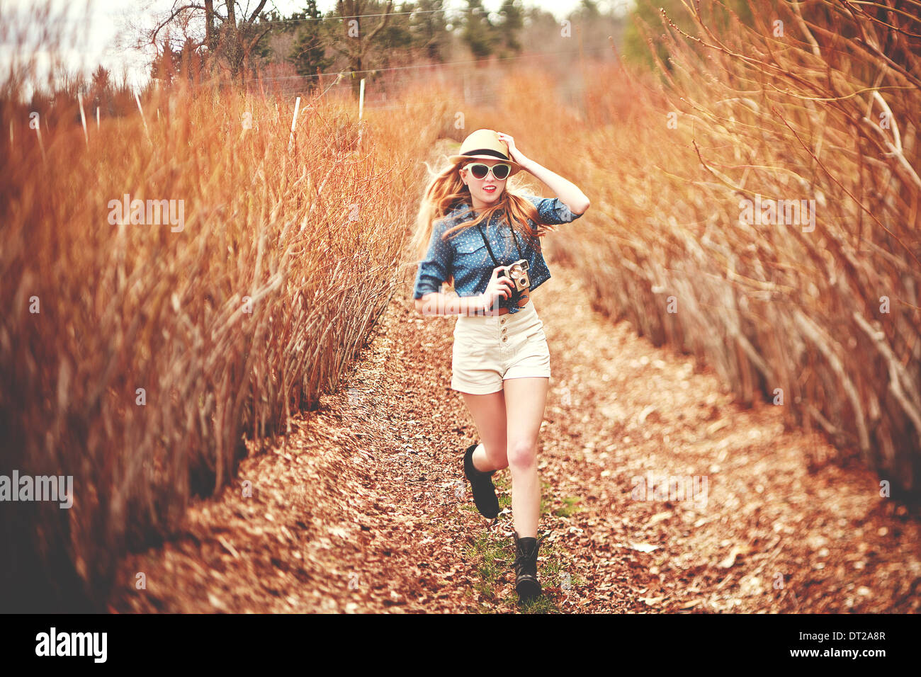 Young woman in fedora hat running towards camera Stock Photo