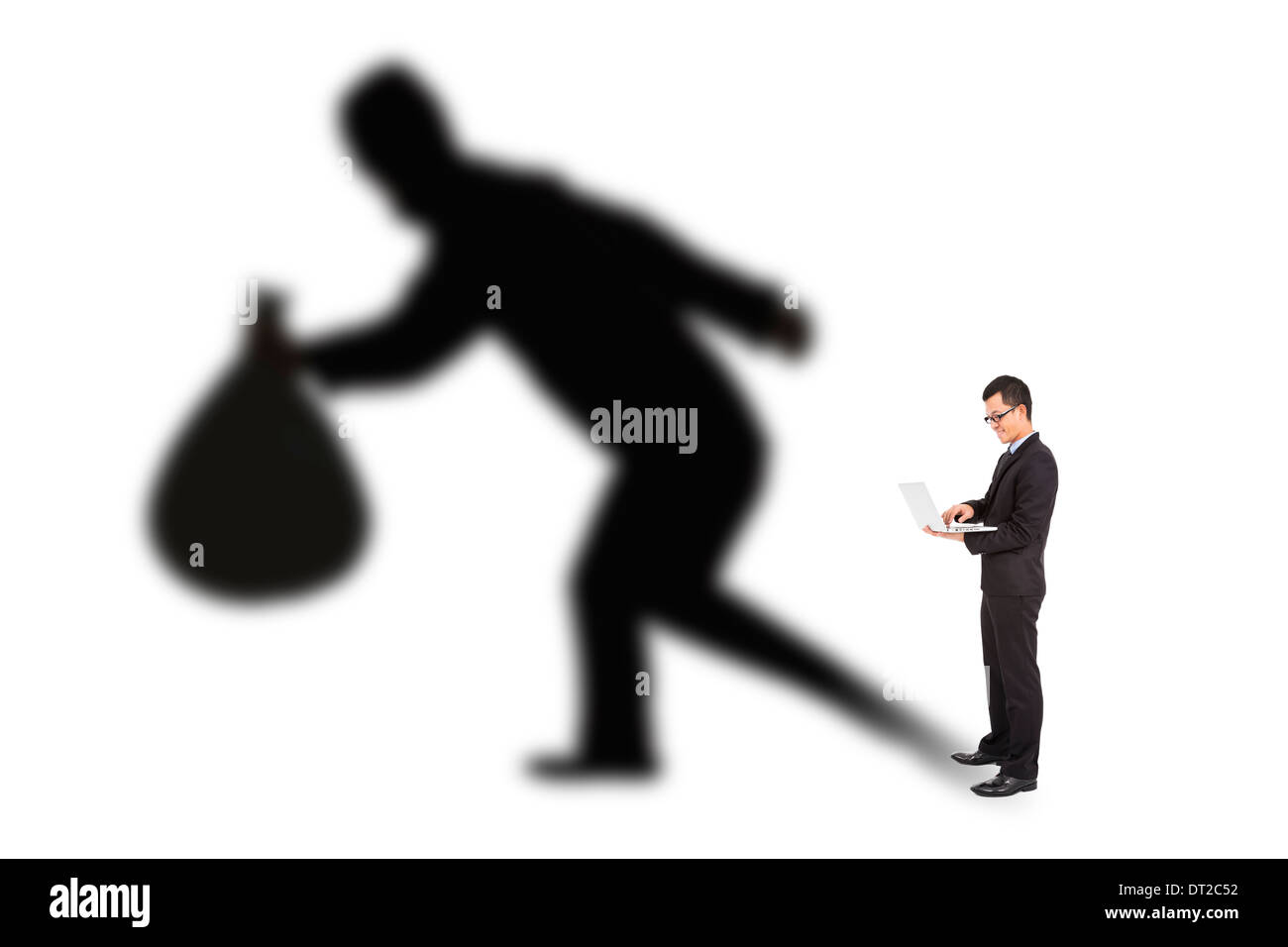 businessman using laptop with thief shadow Stock Photo
