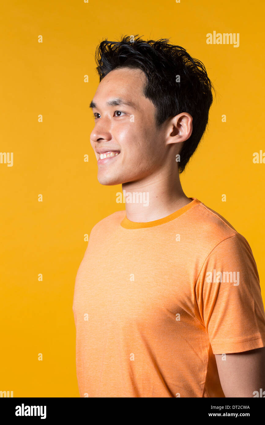 Portrait of Asian man standing against yellow background. Stock Photo