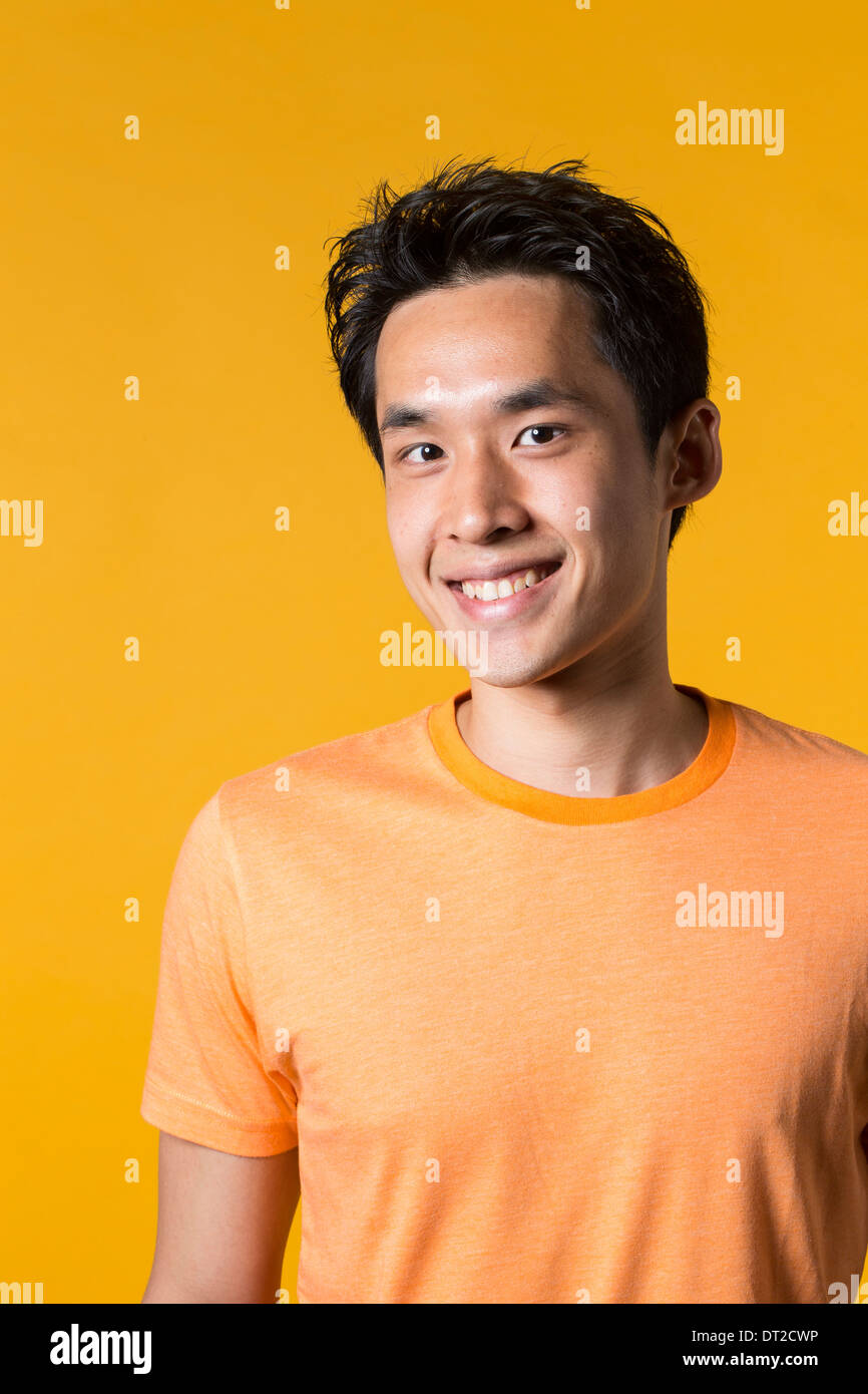 Portrait of Asian man standing against yellow background. Stock Photo