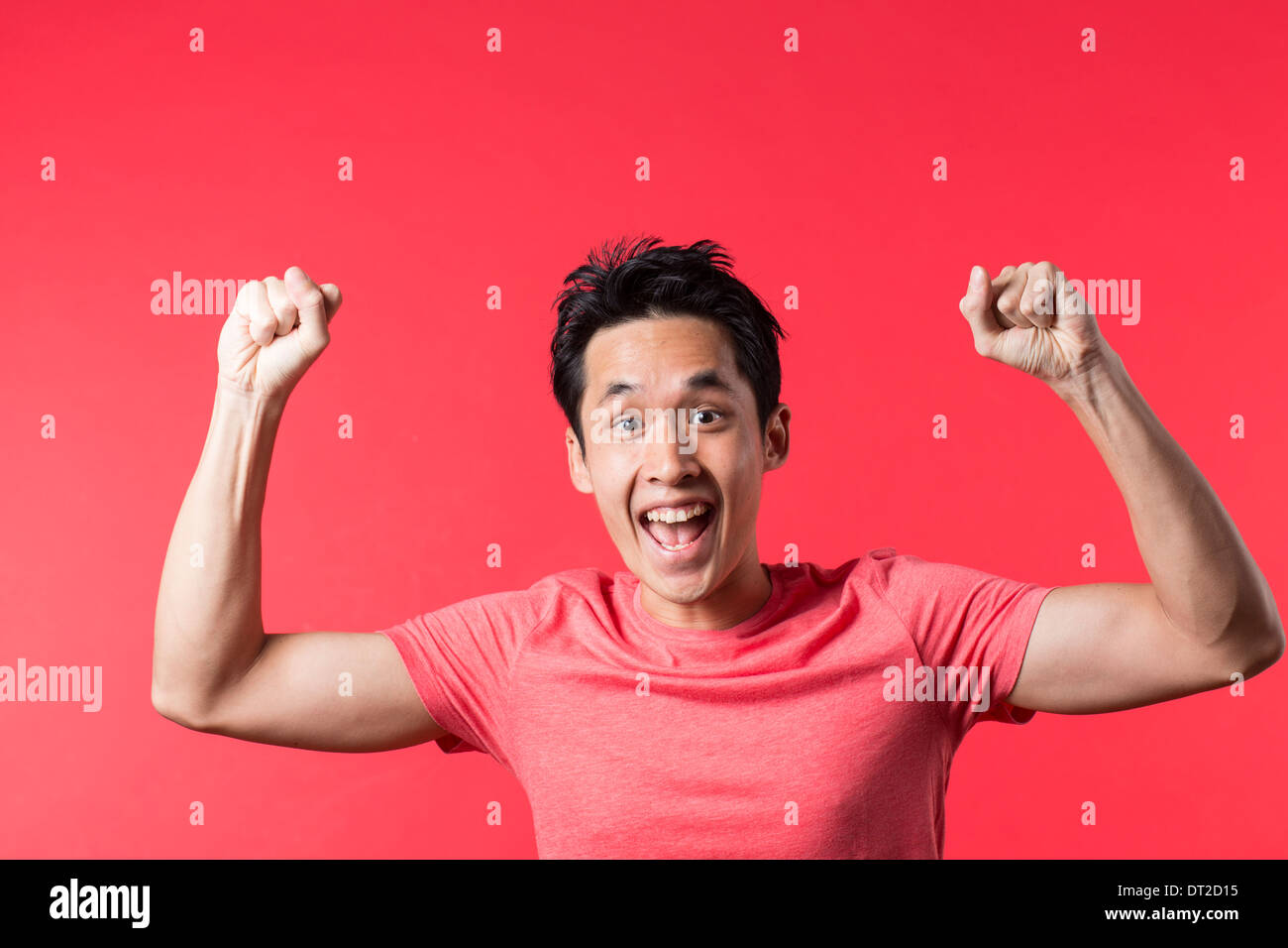Cheerful Asian man celebrating with his arm up. In front of Red background Stock Photo