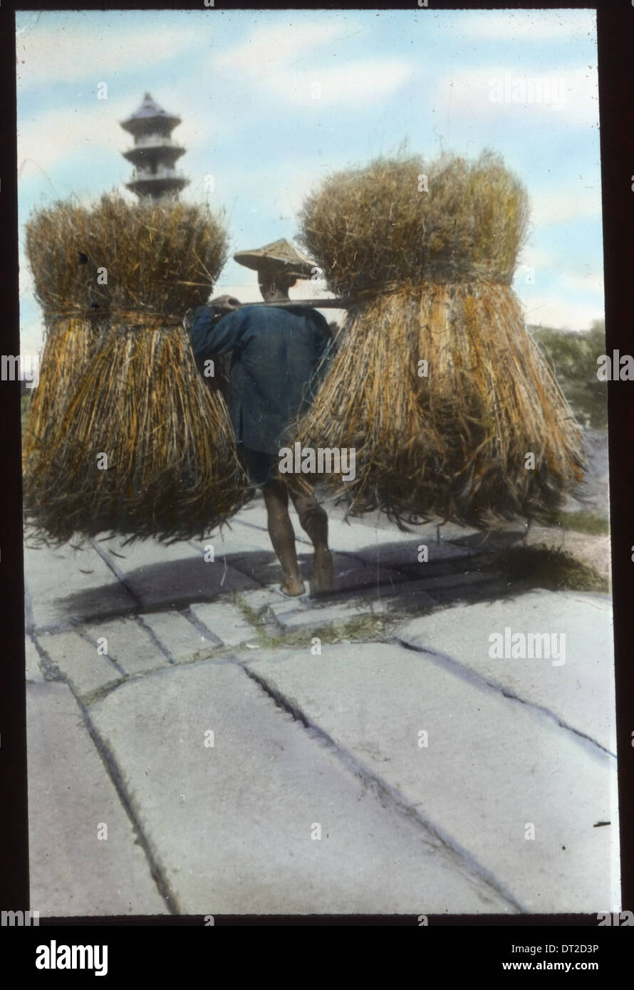 Man carrying two large bundles of straw, China, ca.1917-1923 (IMP-YDS-RG224-OV1- Stock Photo