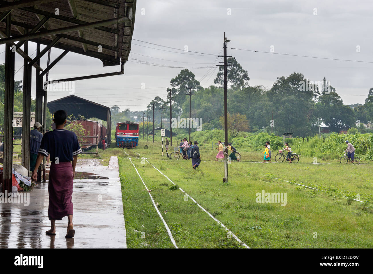 Locals hurrying across the tracks in front of the Mandalay to Pyin Oo Lwin train, Mandalay railway station, Myanmar Stock Photo