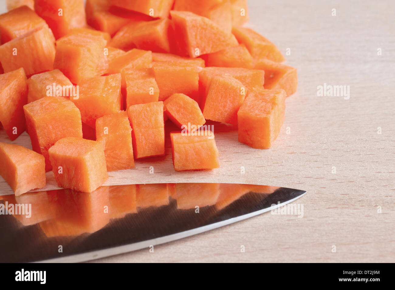 Diced raw carrots with knife on a chopping board Stock Photo