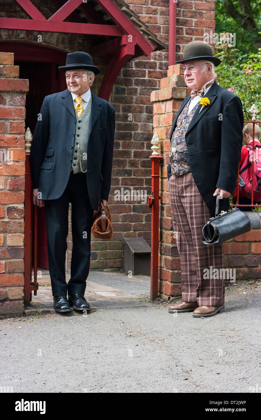 Two senior men in Victorian period costumes outside doctors house looking ahead with interest Blists Hill Telford England. Stock Photo