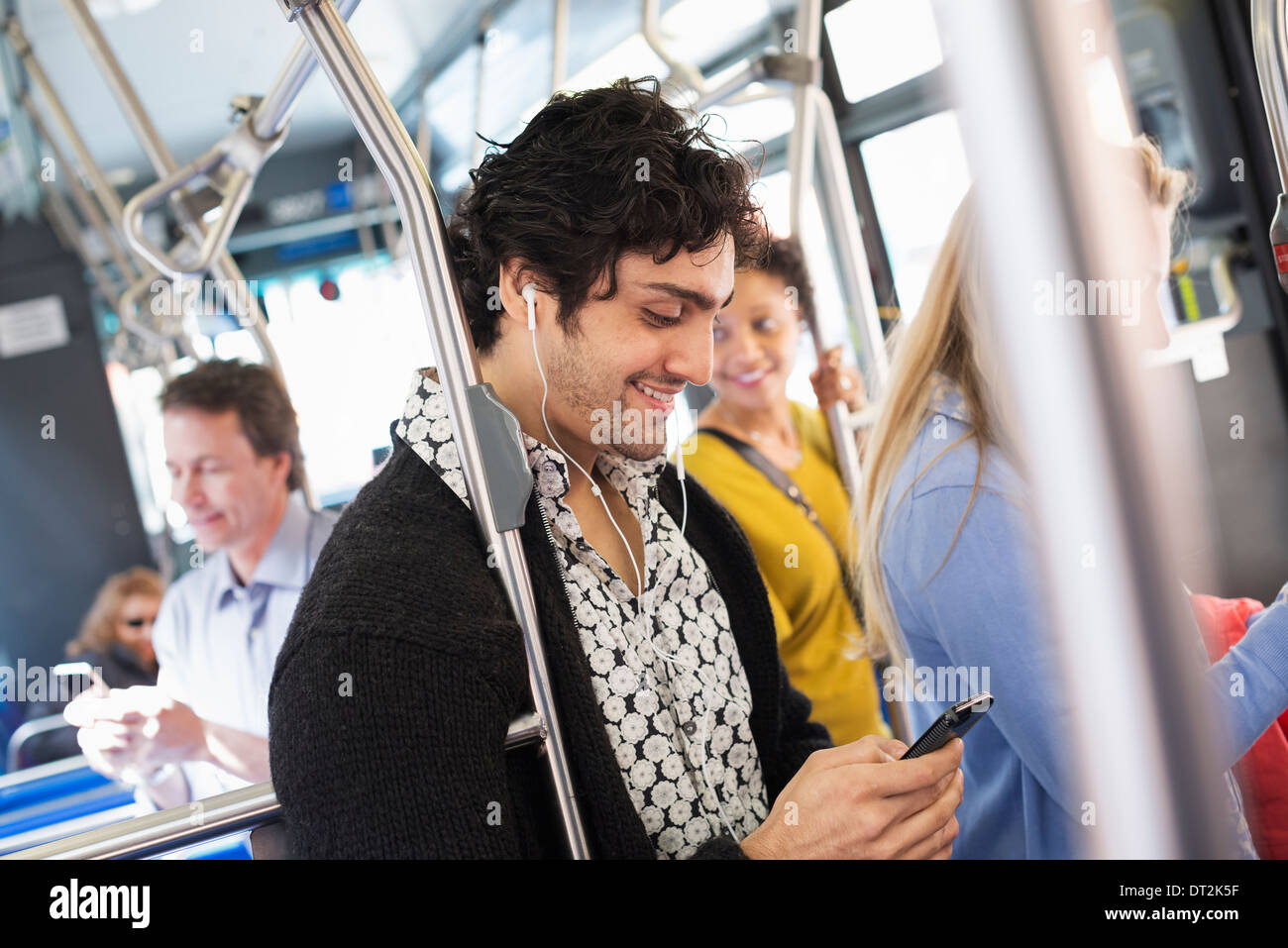 New York City park People men and women on a city bus Public transport Keeping in touch A young man checking his cell phone Stock Photo