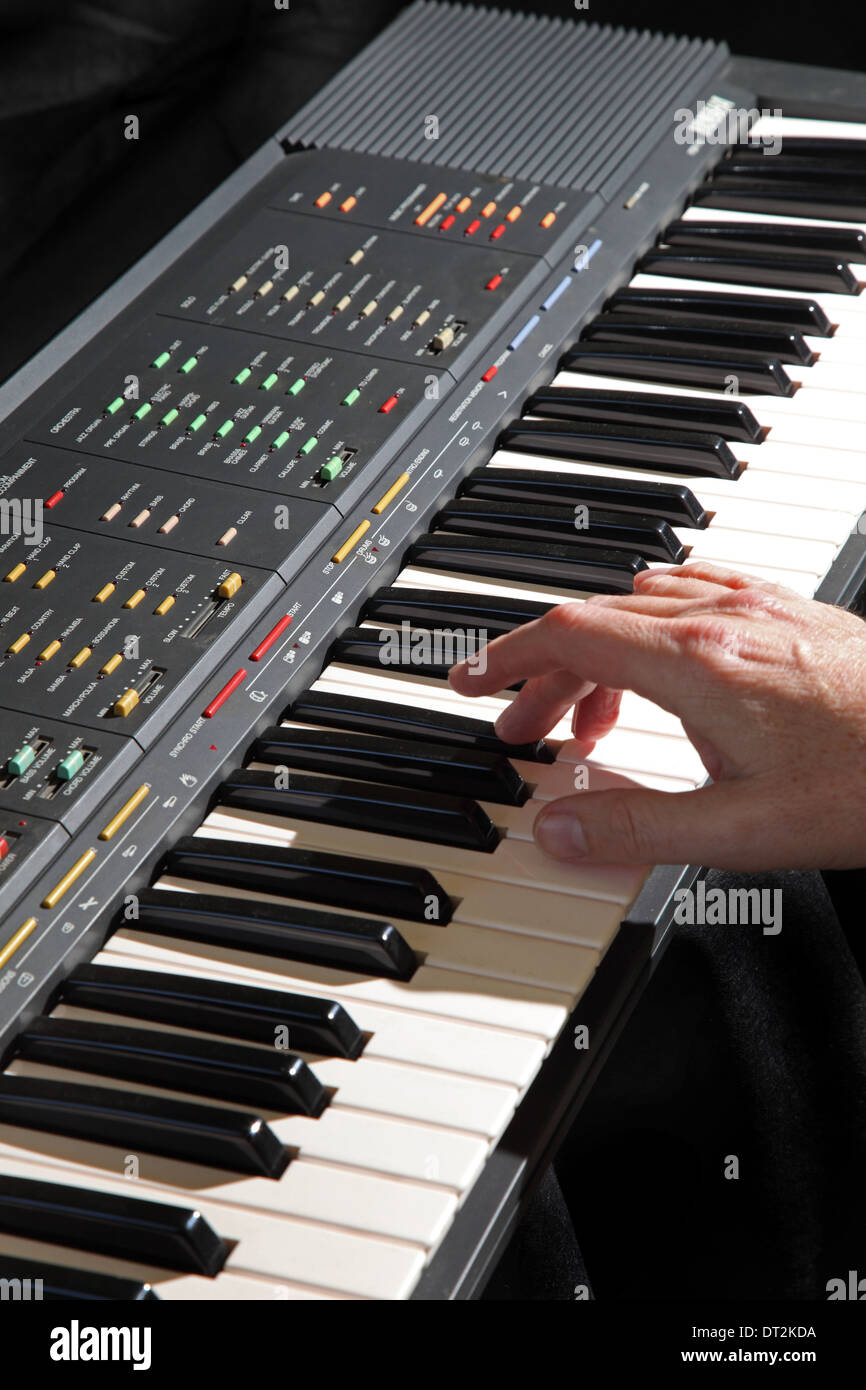 An electronic musical keyboard instrument being played showing the performers right hand. Plain black background. Stock Photo