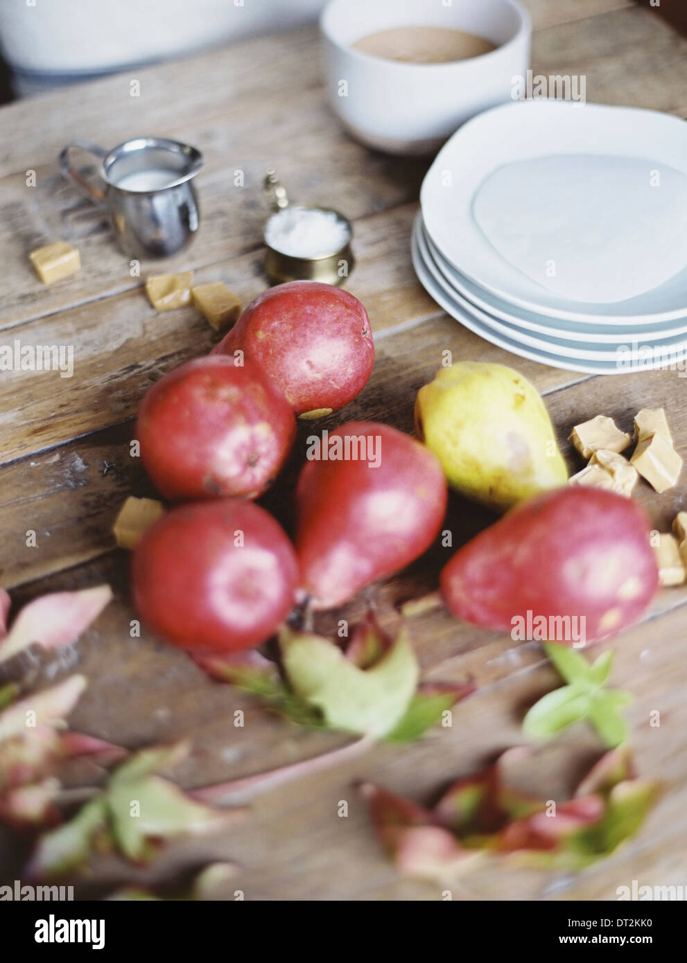 A domestic kitchen tabletop A small group of fresh organic pears and a stack of white plates Stock Photo