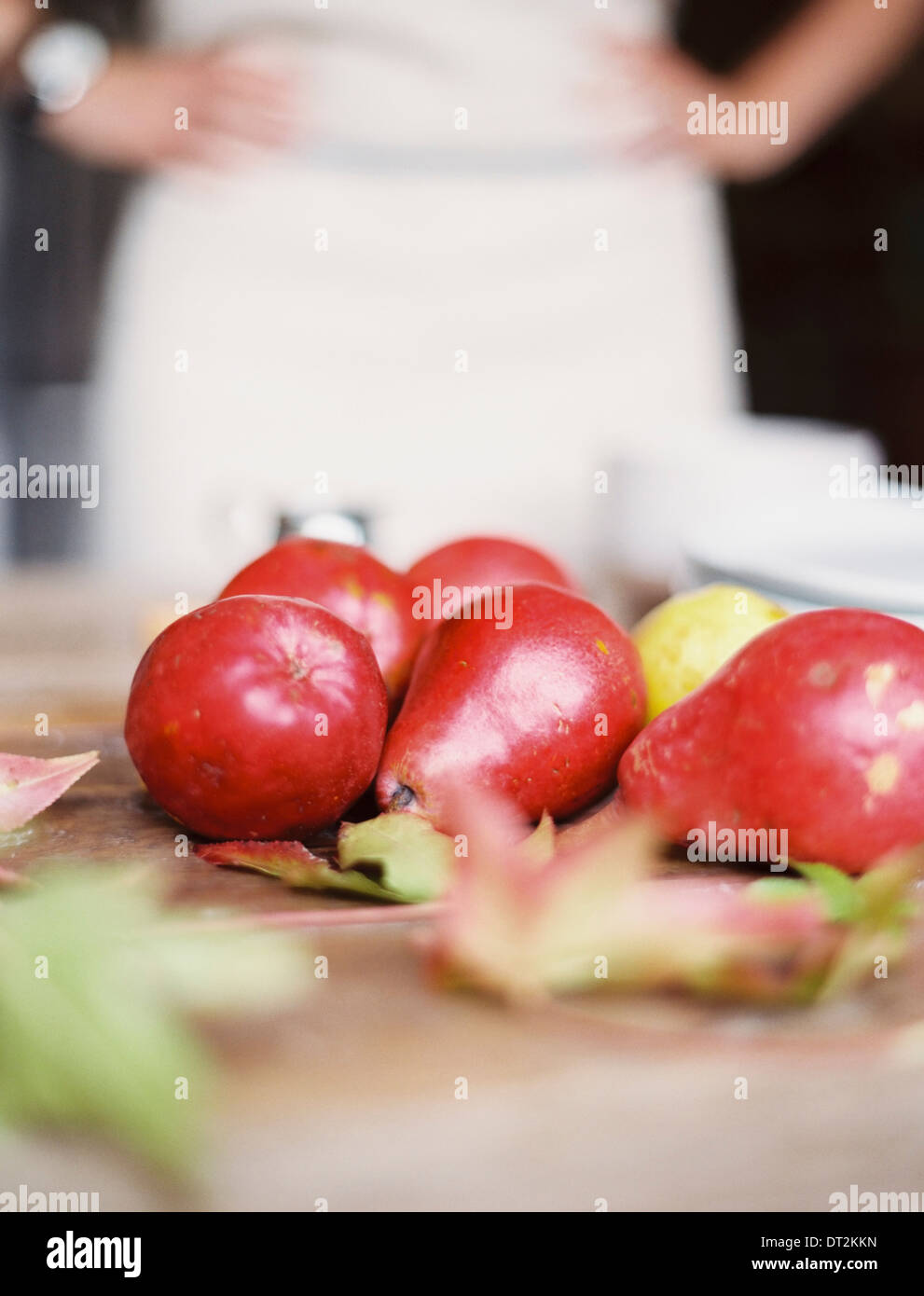 A domestic kitchen tabletop A small group of fresh organic pears and a stack of white plates Stock Photo