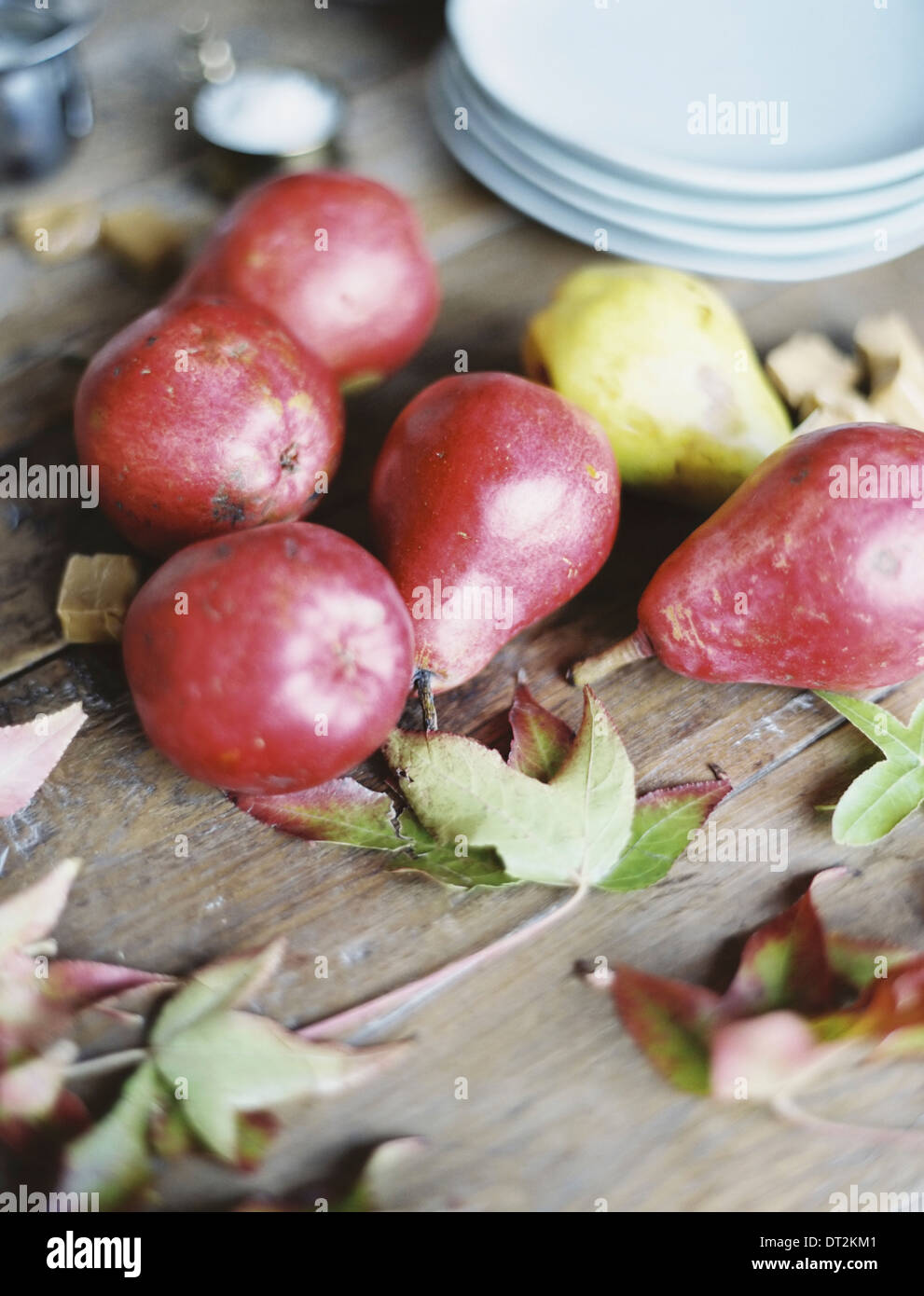 A domestic kitchen tabletop A small group of fresh organic pears and a stack of white plates Stock Photo