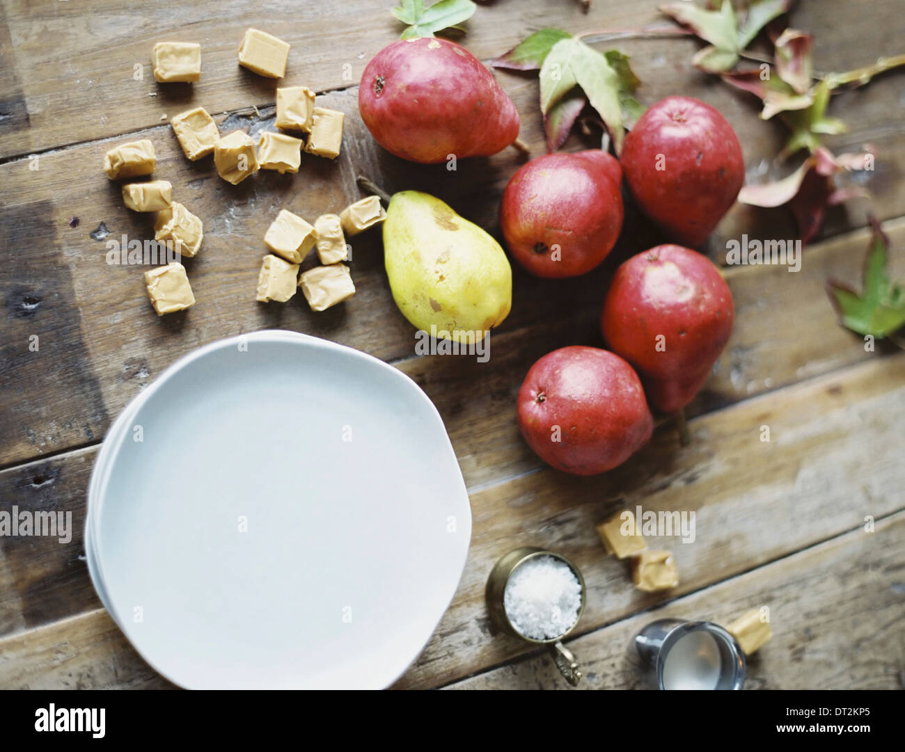 A domestic kitchen tabletop A small group of fresh organic pears and a stack of white plates Stock Photo