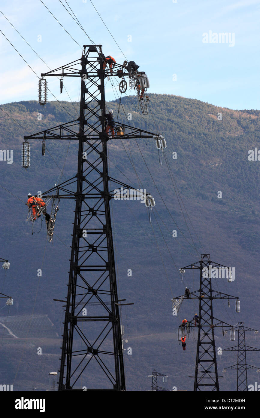 Workers at electricity pylons in Italy. Maintenance work of a high-voltage power line. Stock Photo