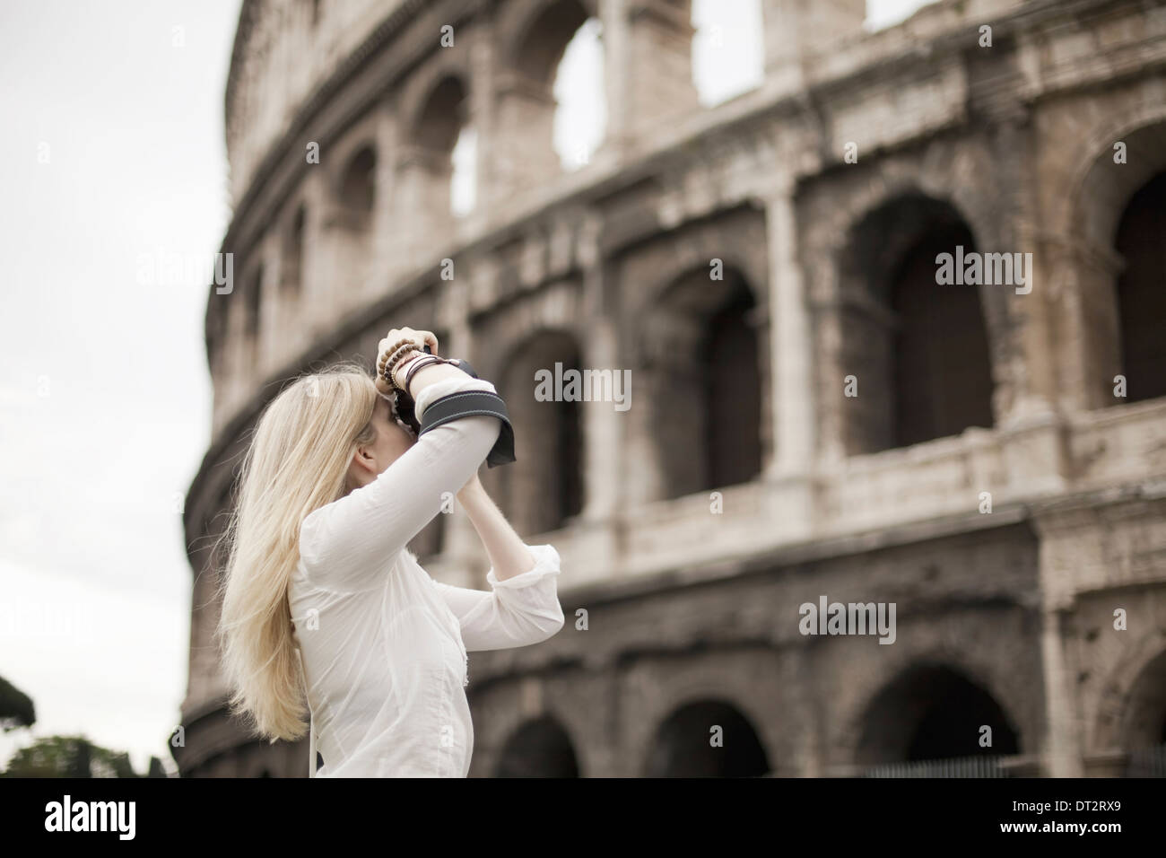 A woman outside the Colosseum amphitheatre in Rome taking photographs Stock Photo