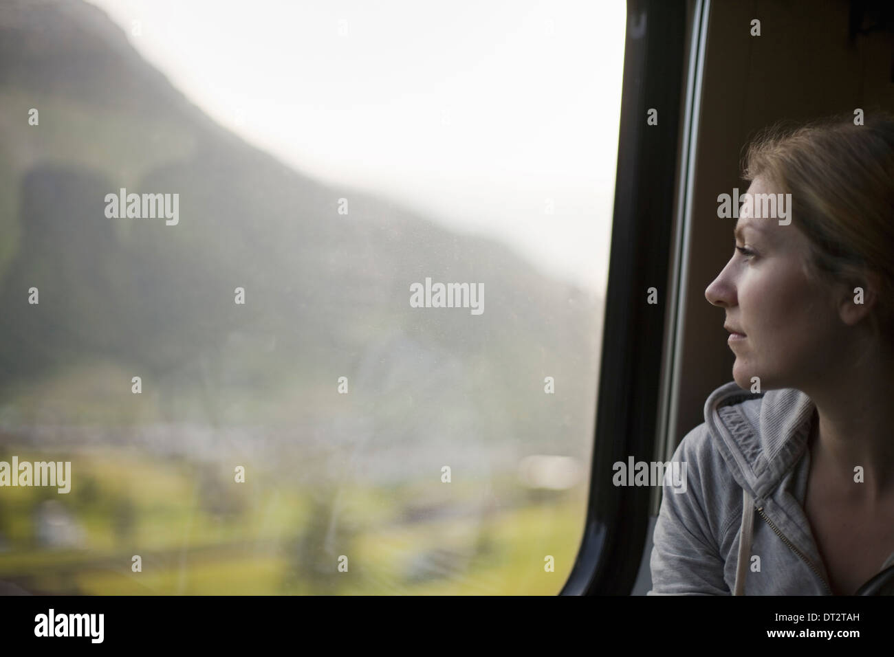 A woman sitting by a train window looking out at the landscape Stock Photo
