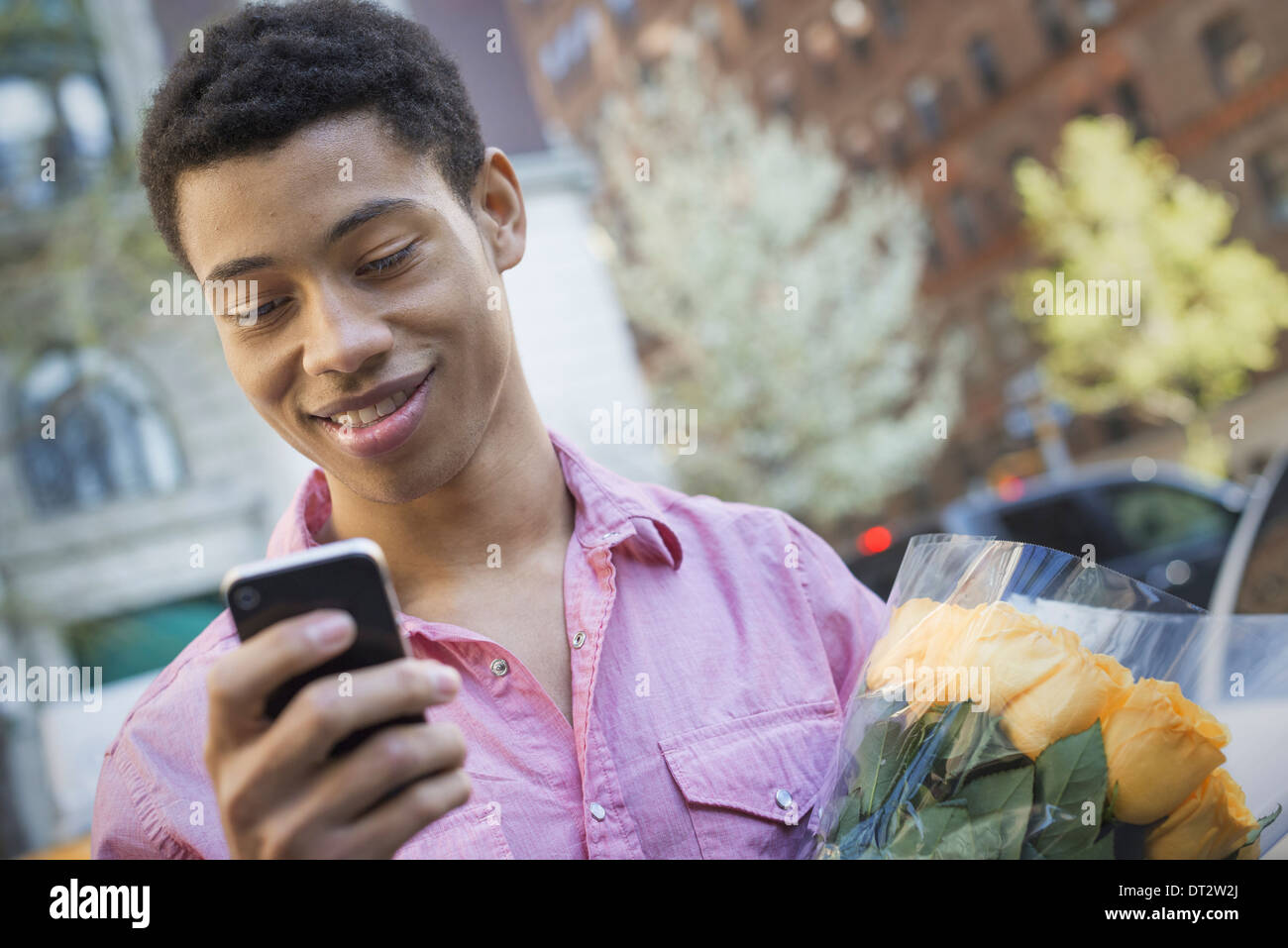 Urban Lifestyle A young man with short black hair wearing a pink casual shirt Holding a smart phone Stock Photo