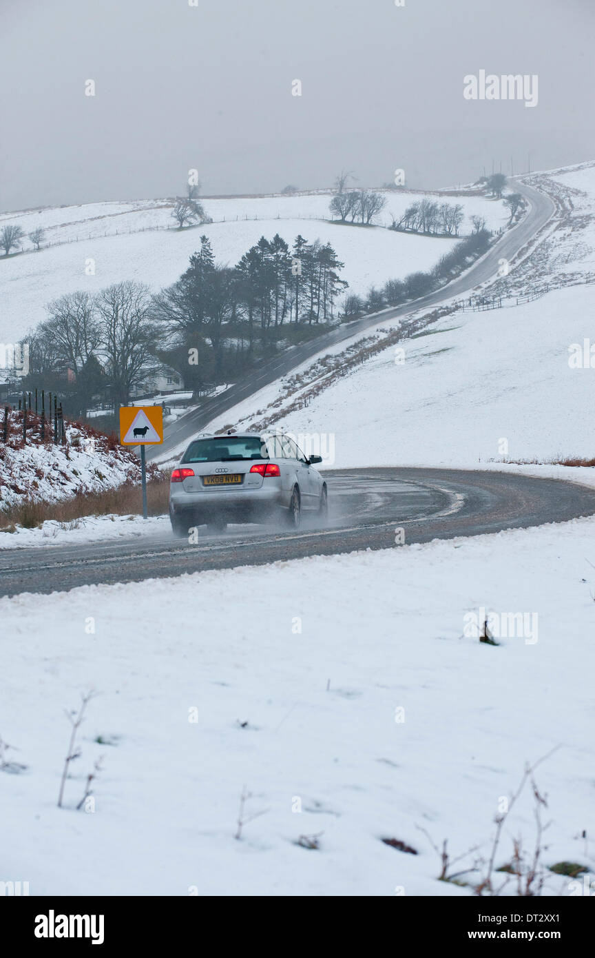 Mynydd Epynt, Powys, Wales, UK. 7th February 2014. vehicles negotiate the snowy road between Builth Wells and Brecon under ominous skies . Snow fell last night on high land in Mid-Wales. Credit:  Graham M. Lawrence/Alamy Live News. Stock Photo