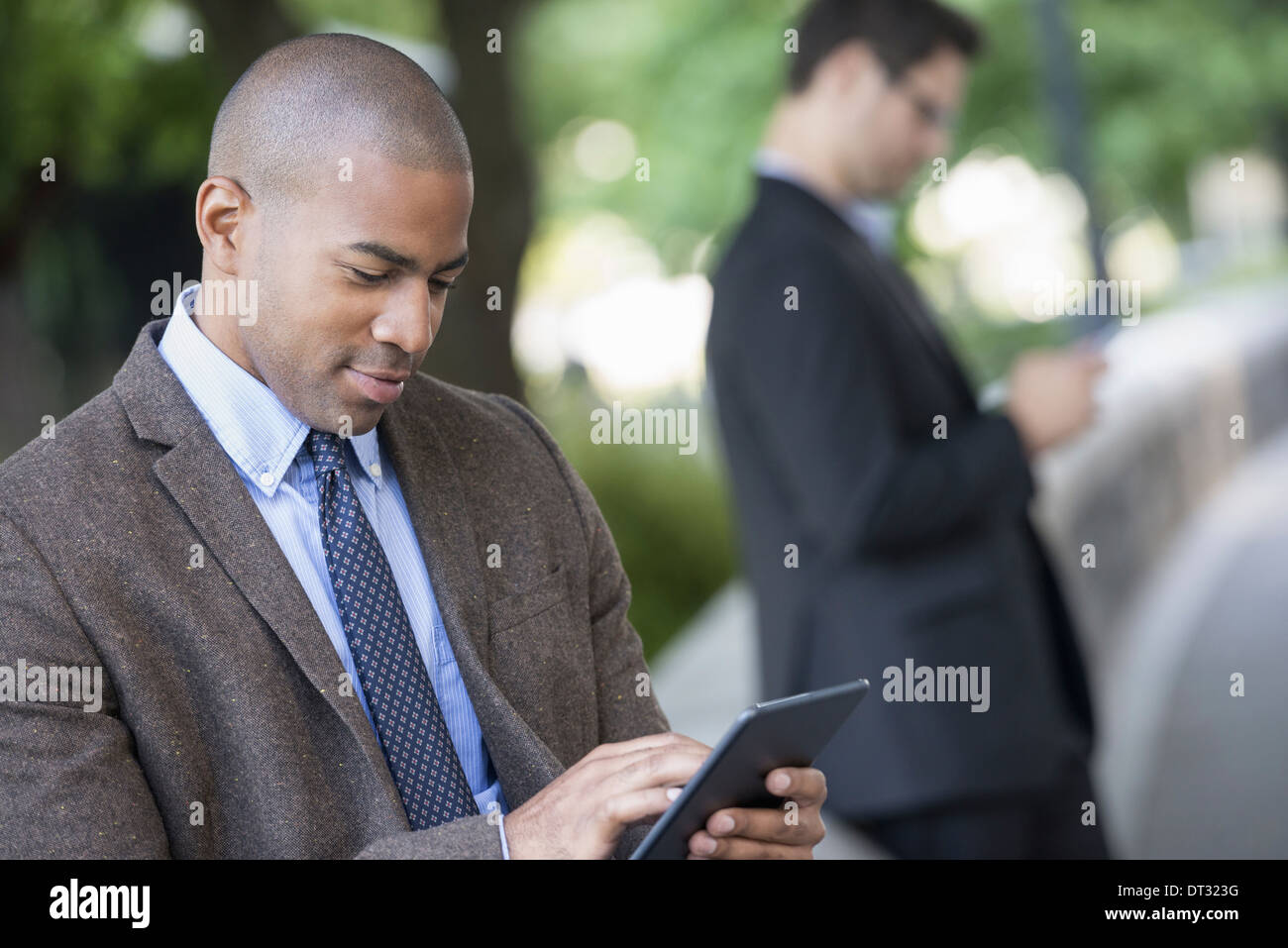Man using a digital tablet and one checking a smart phone Stock Photo